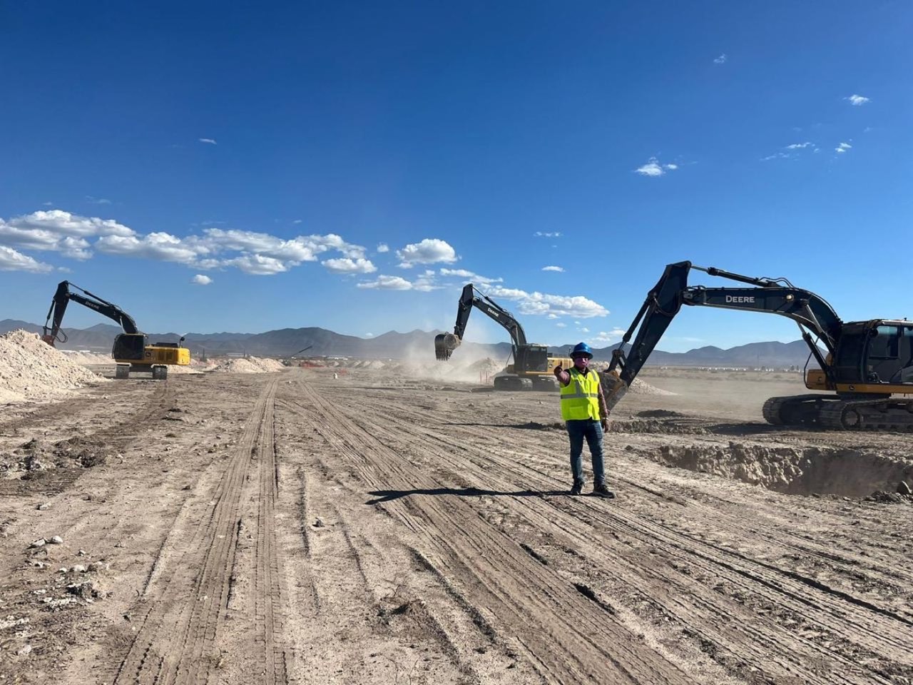 Excavators levelling a large greenfield site, with mountains on the horizon